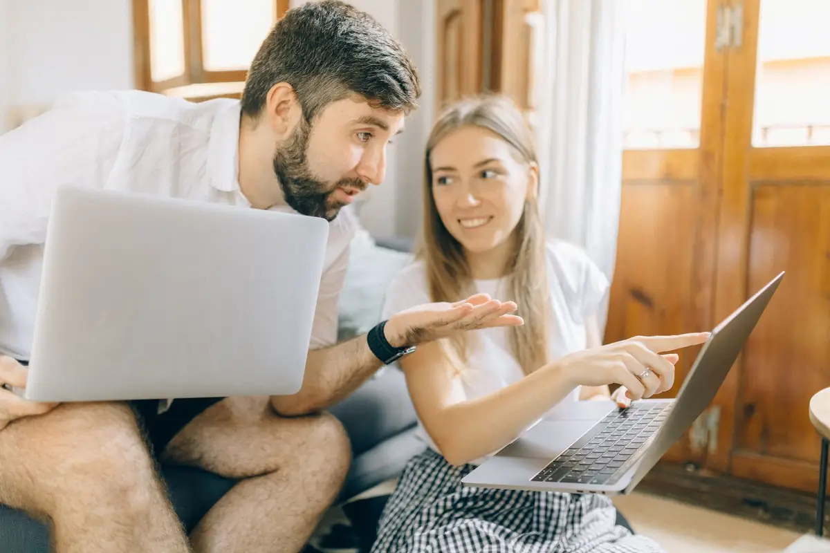 Pareja sonriente revisando opciones de planes de salud en su computador